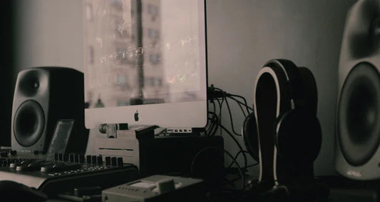 A dark, moody shot of an audio production desk with speakers and a computer.